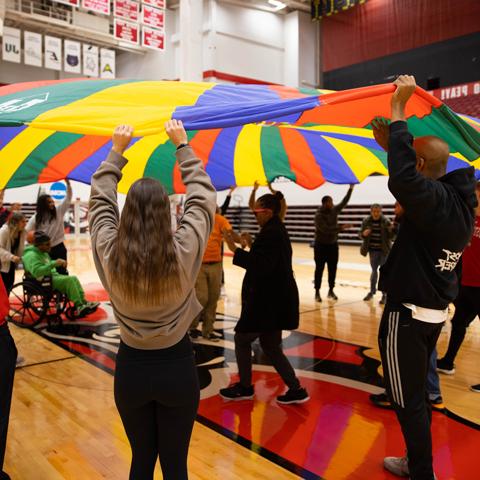 Students working with adults with disabilities in a gym